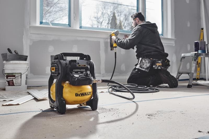 DEWALT draadloze compressor in renovatiekamer, medewerker gebruikt spijkerpistool bij raam.