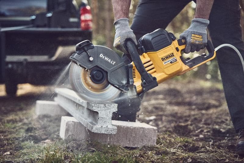 DEWALT zaag snijdt beton buiten; bediener draagt handschoenen voor veiligheid.