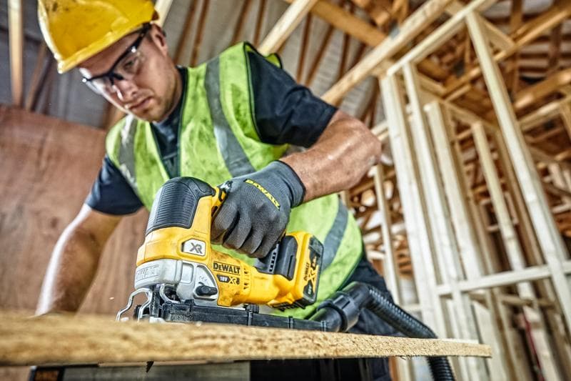 DEWALT DCS334P2 decoupeerzaag gebruikt door een arbeider met veiligheidskleding op een bouwplaats.