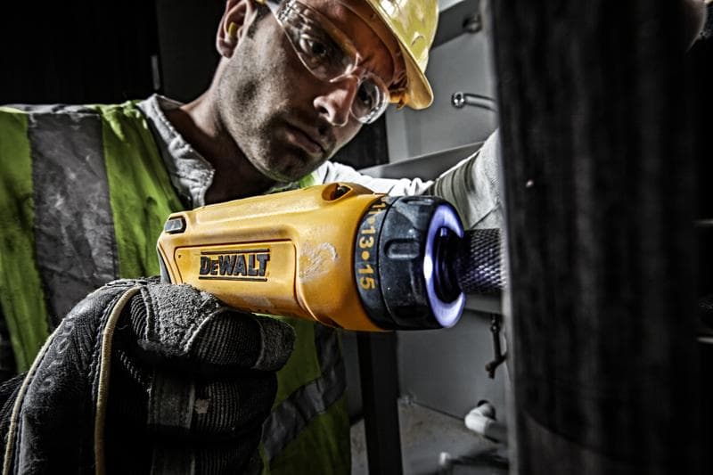 Persoon gebruikt gele DEWALT DCF680G2-schroevendraaier met handschoen in industriële omgeving.