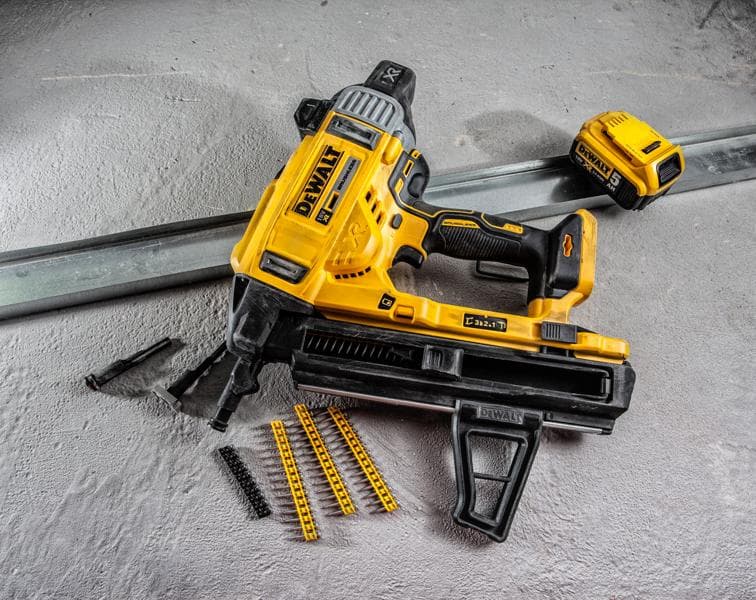 DEWALT DCN890P2 accuspijker met accessoires en bevestigingsmateriaal op betonoppervlak.
