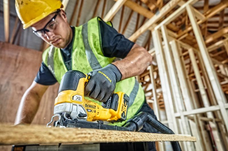 DEWALT DCS334P2 decoupeerzaag gebruikt door een arbeider met veiligheidskleding op een bouwplaats.