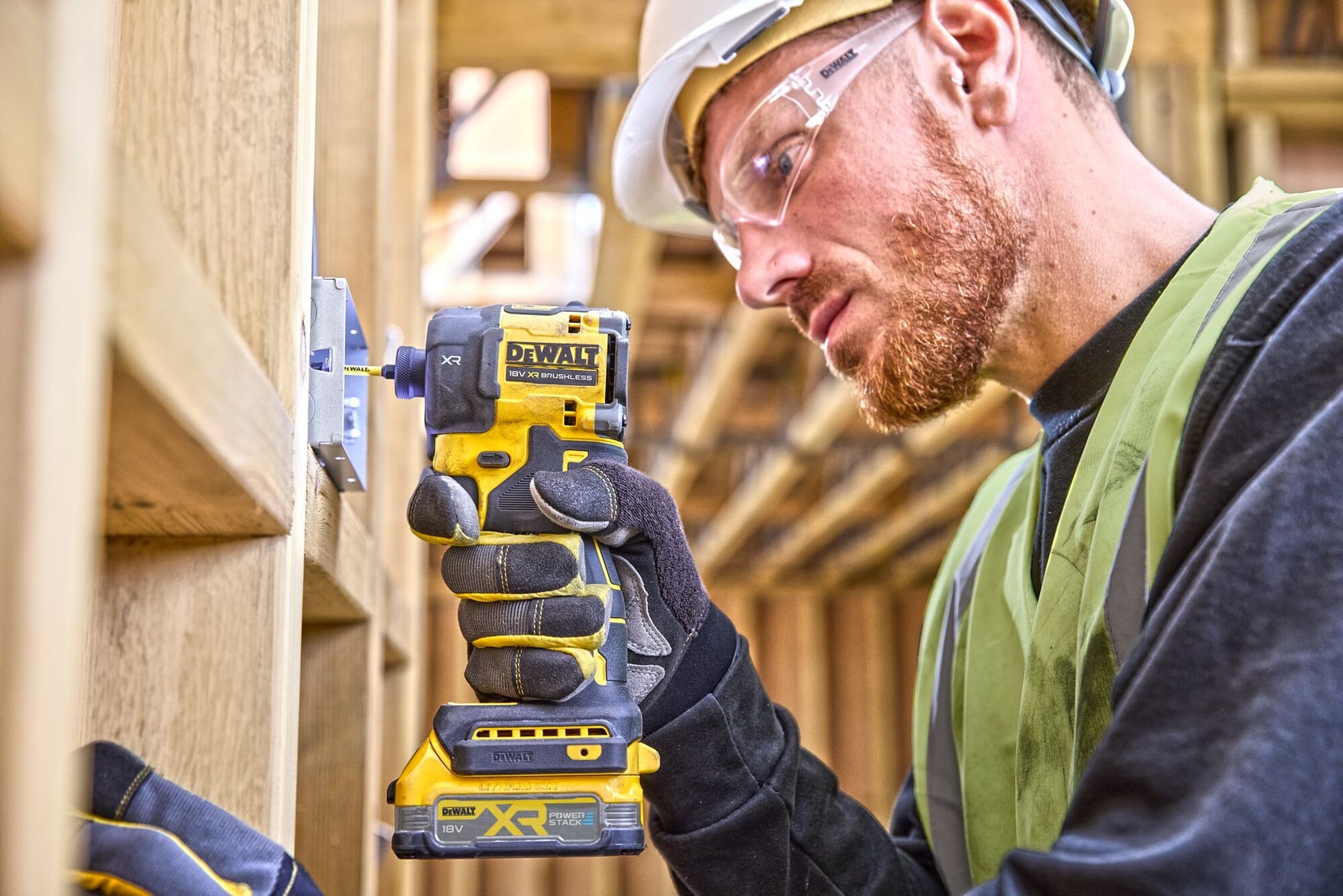 Werker gebruikt een DEWALT DCF870NT accuklopboormachine op houten constructie op bouwplaats.