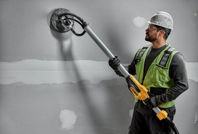 Werker gebruikt DEWALT DWE7800, DWE7800-QS wandschuurmachine op gipswand. Fotografieproduct.